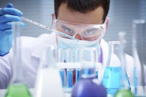 Investigator checking test tubes. Man wears protective goggles